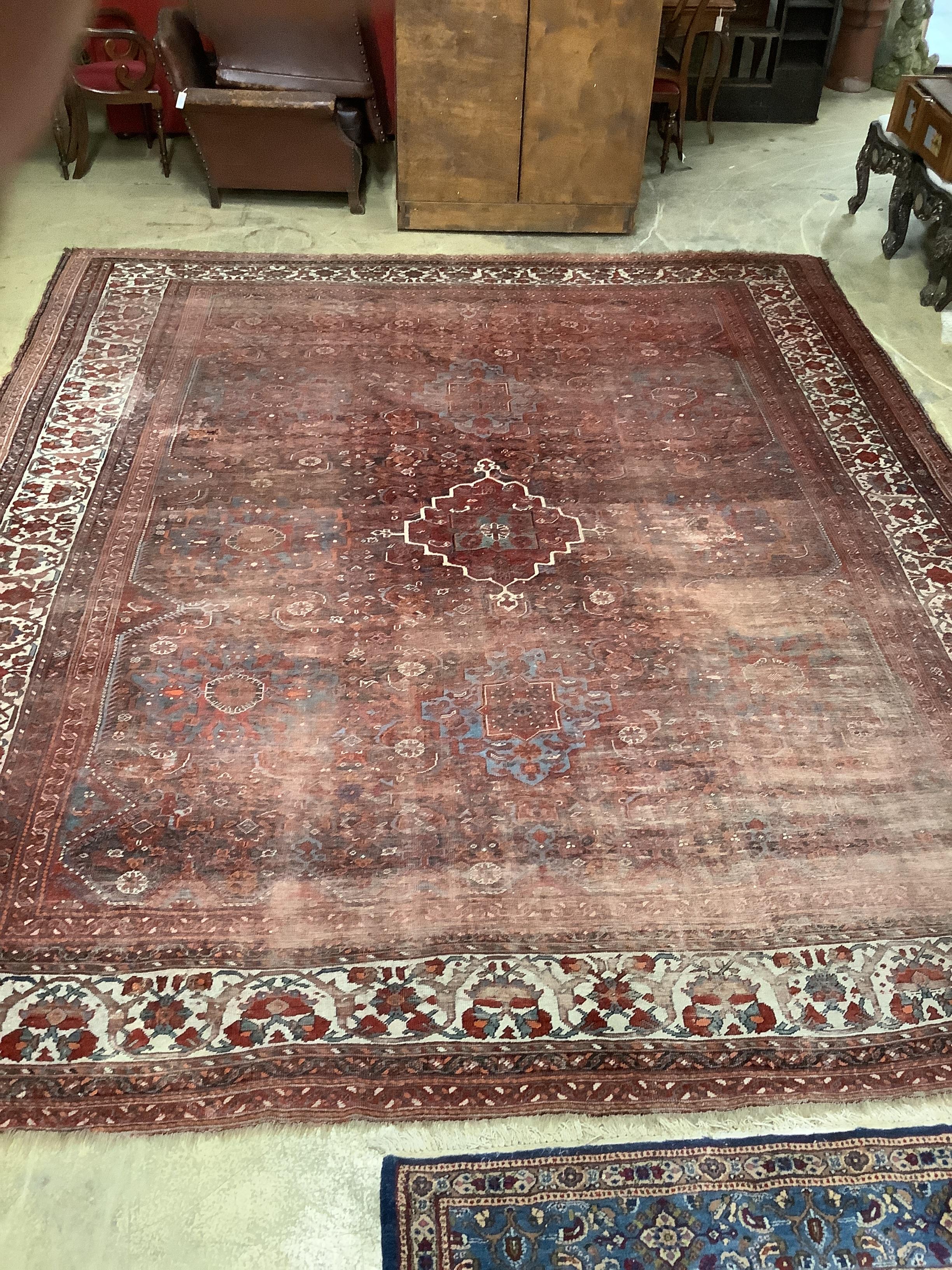 An early 20th century North West Persian red ground carpet, 410 x 348cm, worn and patch repaired.